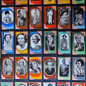 May include: A collection of vintage celebrity trading cards, each featuring a black and white portrait within a decorative frame. The cards showcase various actors and actresses, with a variety of poses and expressions. The frames have a pink and gold border.