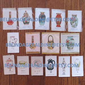 May include: A collection of vintage ceramic art illustrations on fabric, featuring various vases, teapots, and decorative items. The images are printed on small rectangular fabric pieces, arranged on a wooden surface.