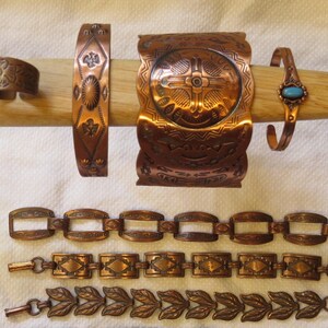 May include: A collection of copper-toned jewelry, including a ring, several bracelets, and chain-style necklaces. The bracelets feature various designs, including embossed patterns and a turquoise stone. The necklaces have rectangular and leaf-shaped links.