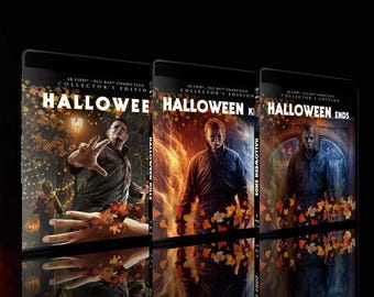 Pode incluir: Três caixas de DVD com fundo preto e design vermelho, laranja e azul. As caixas são para os filmes "Halloween", "Halloween Kills" e "Halloween Ends".