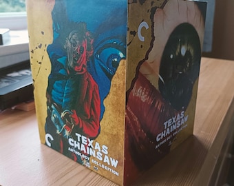 May include: A Blu-ray anthology collection of the horror film "Texas Chainsaw Massacre." The cover art features a gruesome illustration of a figure with a chainsaw and a close-up of an eye. The title is in white and the background is yellow and blue.