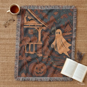 May include: A woven Halloween throw blanket with a dark teal background and a repeating pattern of pumpkins, a ghost, and a haunted house. The blanket has a fringed edge and is made of a soft, comfortable material.