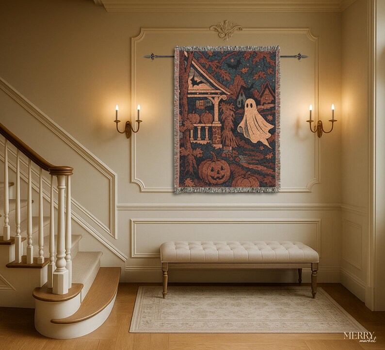 May include: A Halloween tapestry depicting a haunted house, pumpkins, and a ghost in shades of brown, orange, and blue. The tapestry has a fringed edge and is displayed on a wall above a bench in a room with warm lighting.