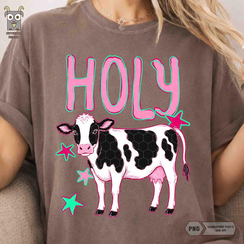Peut inclure: T-shirt marron avec le mot "HOLY" en rose bord&eacute; de vert. En dessous, une vache noire et blanche et des &eacute;toiles roses. Le t-shirt est en mati&egrave;re souple.