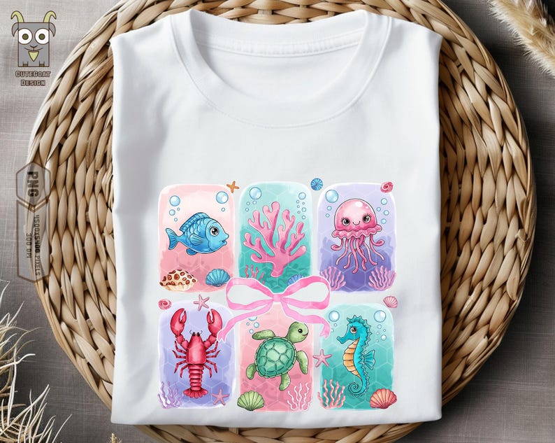 May include: A white t-shirt with a colorful design featuring a blue fish, a pink jellyfish, a red lobster, a green sea turtle, and a pink coral. The design is surrounded by a pink ribbon.