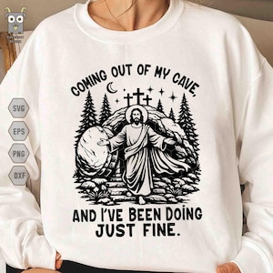 May include: White sweatshirt with a black graphic design. The design features an illustration of Jesus emerging from a tomb, with text that reads "COMING OUT OF MY CAVE, AND I'VE BEEN DOING JUST FINE."