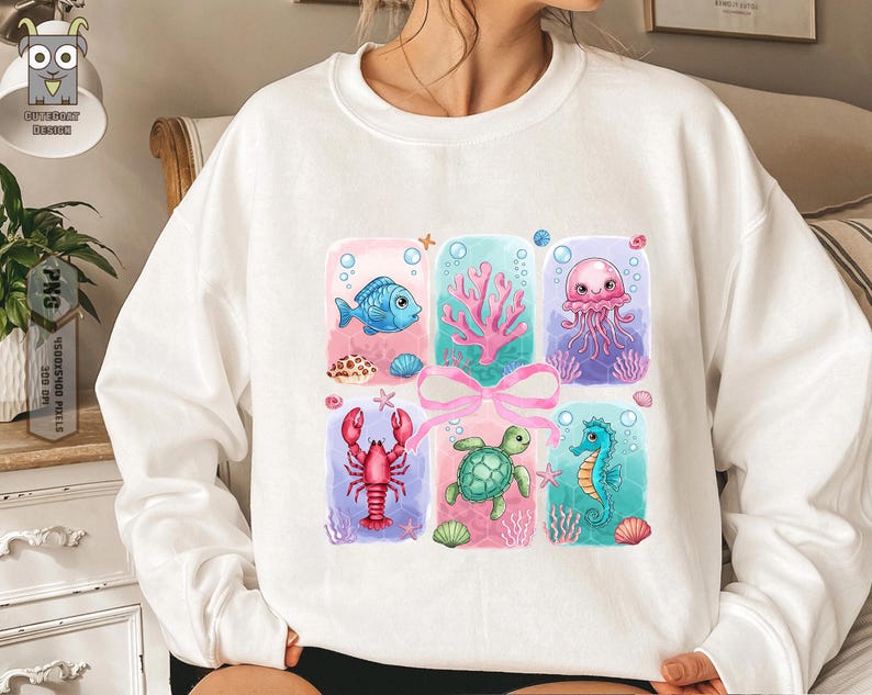 May include: White sweatshirt with a colorful graphic print of a seahorse, a turtle, a lobster, a jellyfish, a fish, and seaweed. The graphic is surrounded by a pink ribbon and blue and white bubbles.