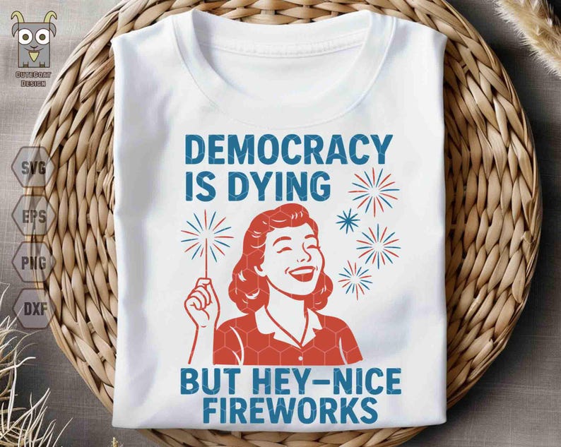 May include: White t-shirt with the text "DEMOCRACY IS DYING BUT HEY-NICE FIREWORKS" in blue. The design includes a red illustration of a woman holding a sparkler and red and blue fireworks.