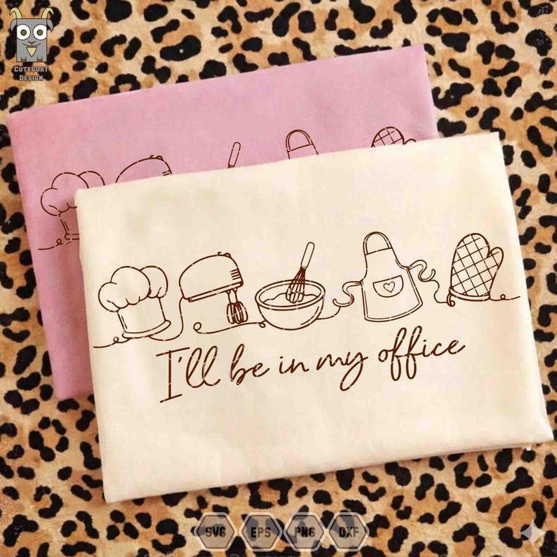 May include: Two folded kitchen towels, one pink and one cream-colored, with a brown line drawing of kitchen tools. The cream towel has the text "I'll be in my office". The drawing includes a chef's hat, mixer, bowl, whisk, apron, and oven mitt.