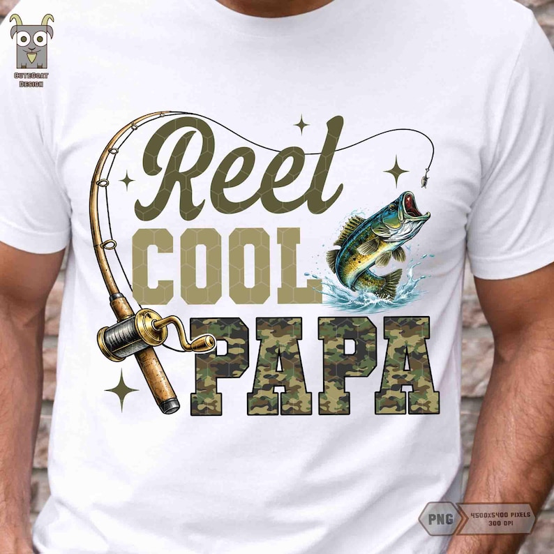 May include: White t-shirt with a fishing-themed graphic. The design includes a fishing rod, a jumping fish, and the words "Reel Cool Papa" in a combination of olive green and camouflage lettering. The shirt is a casual wear item.