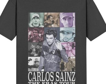 Peut inclure: Un t-shirt gris foncé avec un collage de photos de Carlos Sainz Jr. dans différentes combinaisons de course et casques. Le texte "Carlos Sainz The Eras Tour" est imprimé sous le collage.