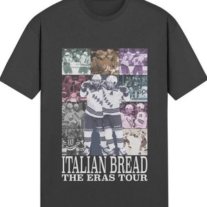 May include: A dark gray t-shirt with a collage of hockey players in various poses. The text "ITALIAN BREAD THE ERAS TOUR" is printed in white on the bottom of the shirt.