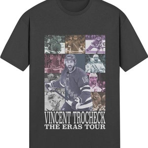 May include: A dark gray t-shirt with a collage of hockey players in various poses. The shirt features the text "Vincent Trocheck The Eras Tour".