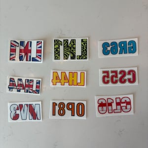 Könnte beinhalten: Neun rechteckige Aufkleber mit Textdesigns. Die Aufkleber zeigen fetten Text in verschiedenen Farben und Mustern, darunter ein Union-Jack-Design, ein grün-schwarzes Wirbelmuster und ein rot-weißes Design.