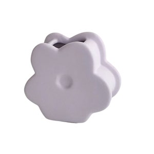 May include: A light purple ceramic flower-shaped vase. The vase has a rounded, three-dimensional shape and a small opening at the top.