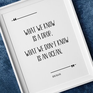 May include: A white framed print with a black and white quote that reads "What we know is a drop, what we don't know is an ocean." The quote is attributed to "BVIC NEWTON".