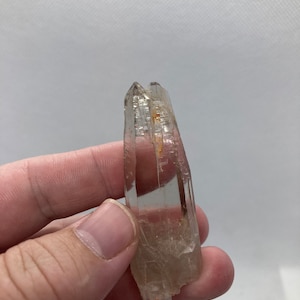 以下が含まれることがあります： ダブルターミネーションとわずかに金色がかった透明な水晶。クリスタルは約5cmの長さで、滑らかで磨かれた表面をしています。