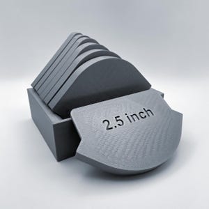 May include: A set of six gray, 2.5 inch diameter, round coasters with rounded edges. The coasters are stacked in a gray box.