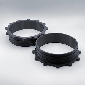 May include: Two black plastic rings with a ridged design and a starburst pattern around the outer edge.