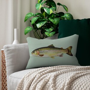 May include: A rectangular decorative pillow with a light green background features a detailed illustration of a fish. The fish has a yellow and brown body with dark fins and is set against a light green backdrop. The pillow is on a gray sofa.