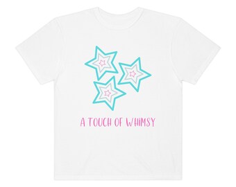 Op de afbeelding: Wit T-shirt met een turquoise en roze ontwerp van drie sterren. De tekst "A touch of whimsy" is in roze onder de sterren gedrukt.