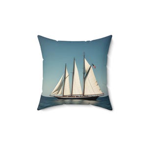 May include: A white sailboat with a brown hull sails on a blue body of water against a clear blue sky. The sailboat has multiple sails and an American flag.