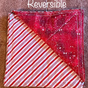 May include: Reversible quilt with a red and white striped pattern on one side and a red and white galaxy print on the other side. The quilt is folded in half, showing both sides.