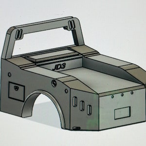 May include: A gray, 3D-rendered model of a vehicle's body, featuring a roll cage, wheel wells, and a rectangular storage area. The text "JD3" is visible on the top. The design is angular and industrial.