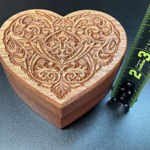 May include: A wooden heart-shaped box with intricate carved details. The box is made of dark wood and has a rich, natural finish.