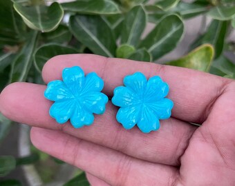 May include: Two turquoise blue flower-shaped cabochons. The cabochons are carved with a detailed flower design.