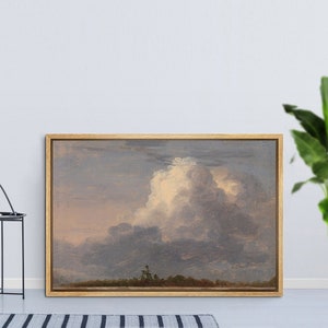 May include: A framed landscape painting depicting a cloudy sky with a large, white cumulus cloud in the center. The sky is a soft blue and gray, with hints of pink and orange in the distance. The painting is set against a white wall.