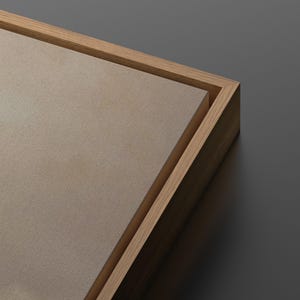 Puede incluir: Primer plano de una impresi&oacute;n en lienzo con una superficie texturizada marr&oacute;n claro, enmarcada en un marco de madera natural. Se ve la esquina del marco, mostrando la veta de la madera. El fondo es gris liso.