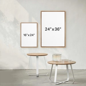 May include: Two wooden picture frames with white mats and black text indicating the size of each frame. The larger frame is 24" x 36" and the smaller frame is 16" x 24". Two white round tables with wooden tops are in the foreground.