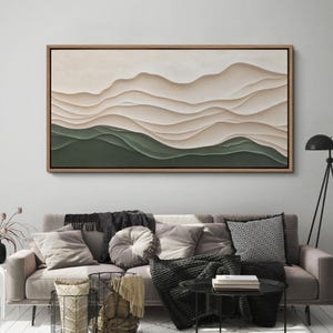 May include: A framed abstract landscape painting with a layered, textured design. The painting features a series of soft, flowing lines in shades of beige and white, creating a sense of depth and movement. The bottom of the painting is a solid green color.