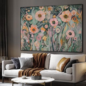 May include: Large floral painting featuring a variety of flowers in shades of pink, orange, and yellow against a dark green background. The artwork is framed and hangs above a white sofa with decorative pillows and a brown throw blanket.
