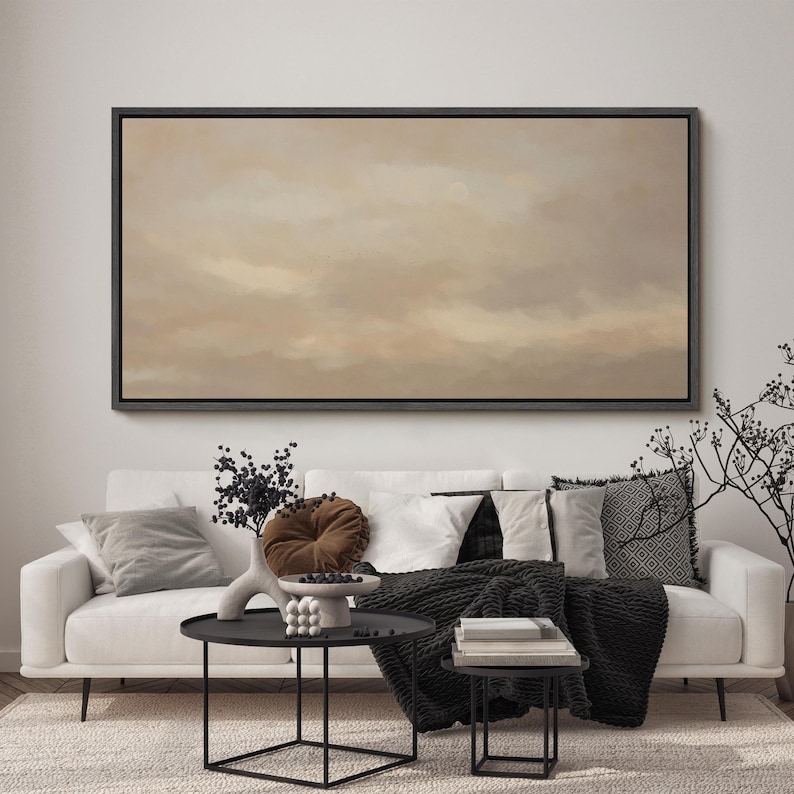 Puede incluir: Sal&oacute;n con un sof&aacute; blanco, cojines y una manta negra. Encima del sof&aacute; hay una pintura abstracta enmarcada. Dos mesas auxiliares negras con objetos decorativos. Una alfombra neutra completa la escena.
