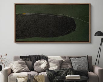 May include: Abstract landscape art print in a wooden frame. The artwork features a dark, textured shape against a green background, with thin white lines and small yellow and black accents. The framed art hangs above a sofa with pillows and blankets.