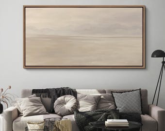 Pode incluir: Uma grande pintura de paisagem retangular em uma moldura de madeira. A obra de arte retrata uma cena serena com uma paleta de cores suaves de bege, castanho e cinza, sugerindo uma vista costeira ou atmosférica. A pintura é exibida acima de um sofá.