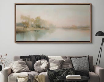 Op de afbeelding: Een ingelijst landschapsschilderij dat een serene waterpartij toont. Het kunstwerk heeft een zacht kleurenpalet van gedempte groenen, blauwen en roze tinten, met bomen en hun weerspiegelingen in het water. Het schilderij wordt boven een bank weergegeven.
