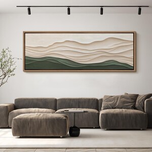 May include: A long, horizontal abstract painting with a layered, textured design. The painting features a series of soft, flowing lines in shades of beige and brown, creating a sense of depth and movement. The bottom portion of the painting is a solid green color.