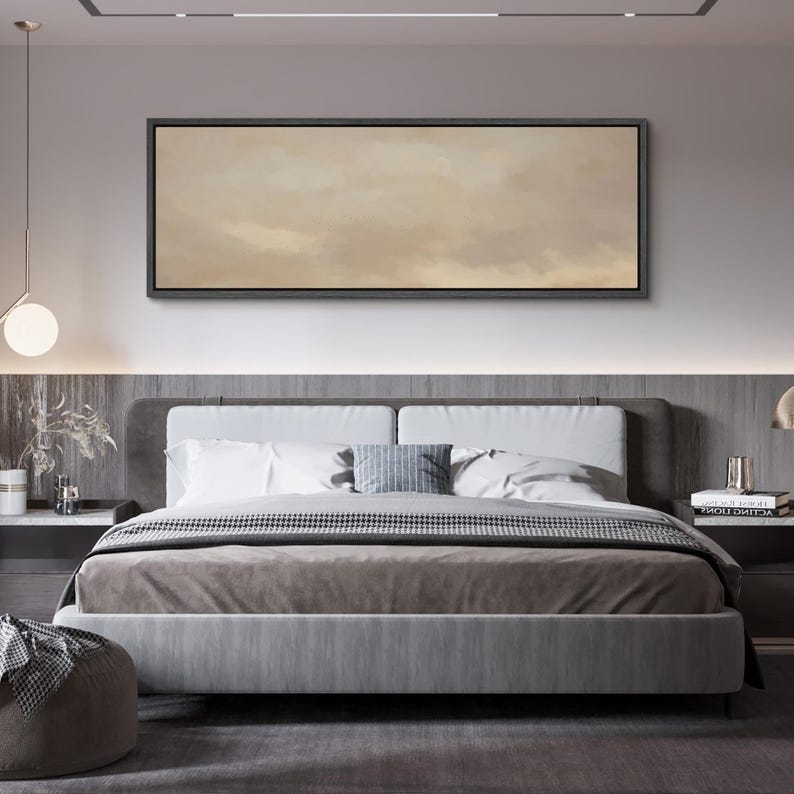 Puede incluir: Un dormitorio moderno con una cama grande, un cabecero tapizado gris y un edred&oacute;n de tonos neutros. Encima de la cama cuelga una obra de arte rectangular con un paisaje abstracto y apagado. La habitaci&oacute;n est&aacute; decorada con colores suaves y neutros.