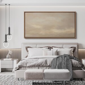 Puede incluir: Una escena de dormitorio con una cama con ropa de cama blanca, almohadas y una manta estampada en blanco y negro. Encima de la cama hay una gran obra de arte enmarcada con una paleta de colores neutros. La habitaci&oacute;n est&aacute; decorada en tonos neutros.
