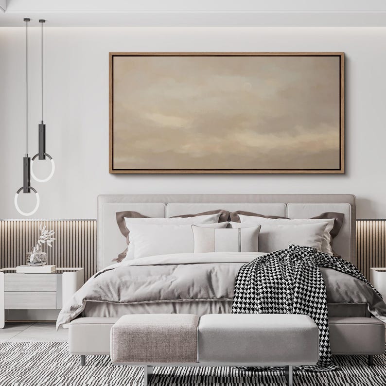 Puede incluir: Una escena de dormitorio con una cama con ropa de cama blanca, almohadas y una manta estampada en blanco y negro. Encima de la cama hay una gran obra de arte enmarcada con una paleta de colores neutros. La habitaci&oacute;n est&aacute; decorada en tonos neutros.
