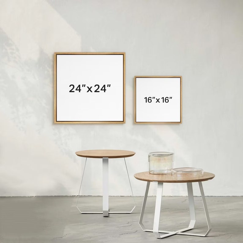 May include: Two square wooden picture frames with white mats and black text. The larger frame is 24" x 24" and the smaller frame is 16" x 16". Two white metal side tables with round wooden tops.