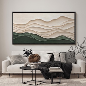 May include: A white couch with black throw blankets and pillows in a living room with a large abstract painting of beige and green waves hanging on the wall. There are two black coffee tables in front of the couch.