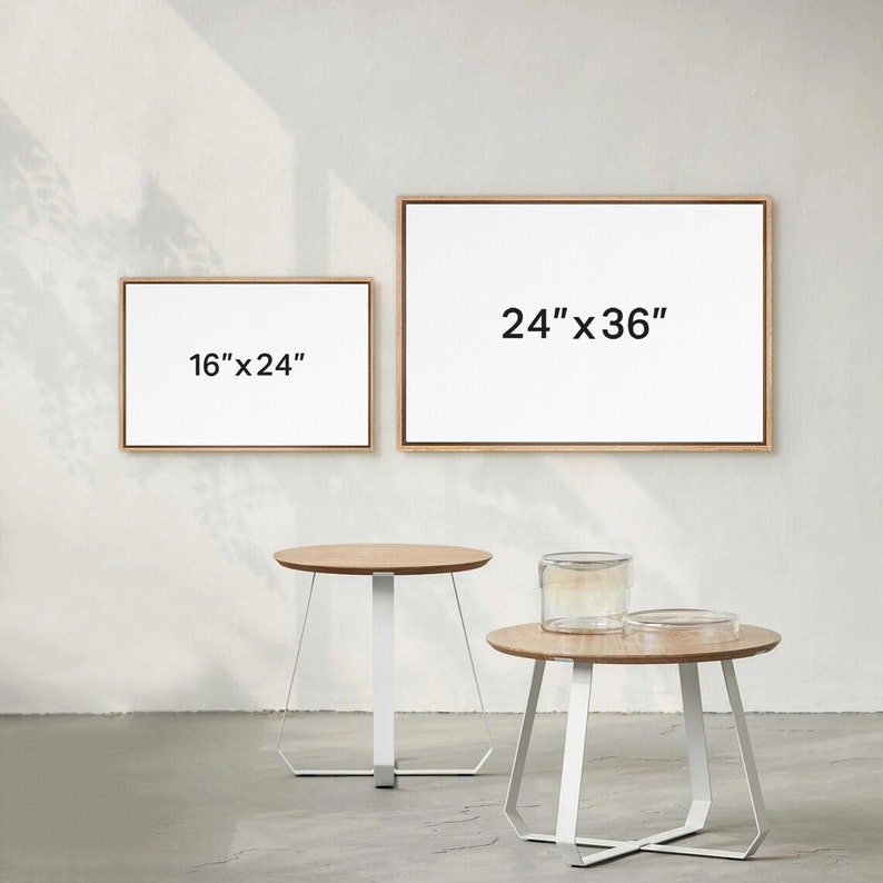 May include: Two wooden framed canvases with white backgrounds and black text. The larger canvas is 24" x 36" and the smaller canvas is 16" x 24". Two white side tables with wooden tops are in the foreground.