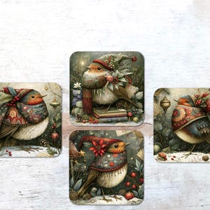 May include: Three square coasters featuring illustrations of robins wearing patterned winter clothing and scarves. The birds are surrounded by festive elements like holly, berries, and ornaments in a snowy, woodland-inspired setting with muted tones.