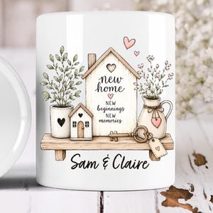 Puede incluir: Una taza de cerámica blanca con una ilustración impresa de un estante de madera que sostiene un letrero en forma de casa, una planta en maceta, una casa pequeña y una jarra con flores. El letrero dice new home, new beginnings, new memories.