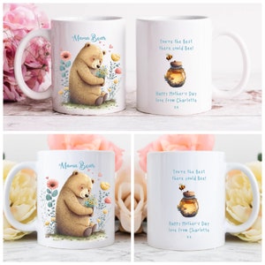 May include: Two white ceramic mugs with a floral design. One mug features a cartoon bear holding flowers and the text "Mama Bear". The other mug features a cartoon bee and a jar of honey with the text "You're the Best there could Bee! Happy Mother's Day love from Charlotte XX".
