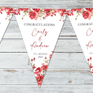 Puede incluir: Guirnalda triangular blanca con detalles florales rojos y el texto "CONGRATULATIONS Carly & Andrew 17th August 2025". La guirnalda está decorada con rosas rojas y hojas verdes, ideal para una boda o aniversario.